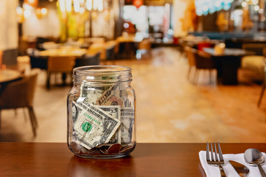 Tip jar in restaurant dining room. Service industry tipping, minimum wage and gratuity concept.