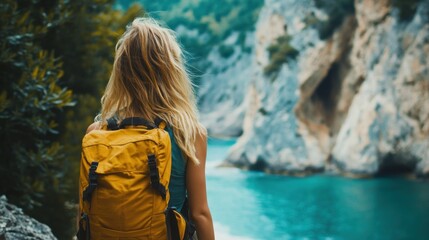 Obraz premium Woman with Yellow Backpack Gazing at a Turquoise Gorge
