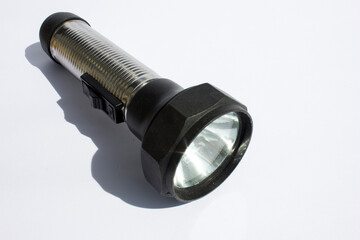 Depicted in the photograph is a single handheld flashlight. Its sturdy construction, ribbed metal body, and contrasting black rubber elements highlight its design and portability. 