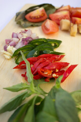 Fresh ingredients like tomatoes, garlic, and sliced chillies on a wooden cutting board, ready for cooking.