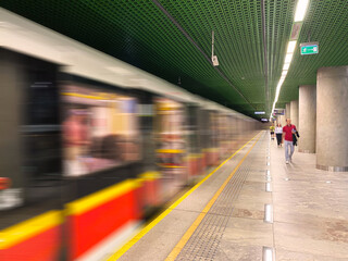 Warszawskie metro w ruchy, stacja metra. Jadące wagony, ludzie na peronie, platformie. © malgo_walko
