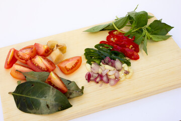 Fresh ingredients like tomatoes, garlic, and sliced chillies on a wooden cutting board, ready for cooking.