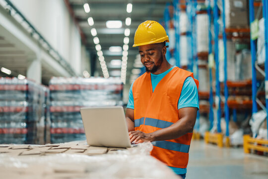 Male african american warehouse worker using a laptop in a modern facility.