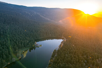 A blue lake hidden among the trees in Golcuk National Park. Aerial photo of the forest and bright landscape in autumn. Sunset. Bolu, Turkey.