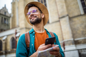 Male tourist looking at map on his phone while touring a foreign city.