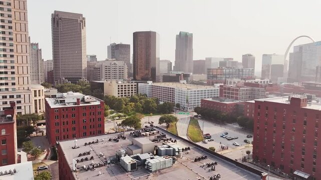 Drone flying down misc street in downtown Saint Louis, Missouri city during sunrise with cars driving down the street.