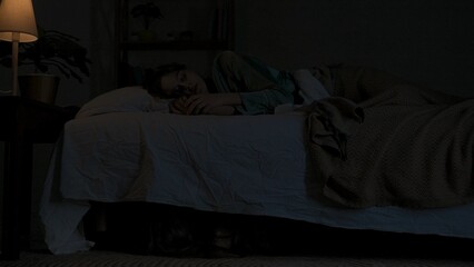 Woman sleeping in bed in dark apartment room, monster hiding under bed. Storm and lightning flash lights outside. Halloween horror concept. © kinomaster