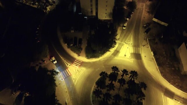 Vista a&eacute;rea noturna da cidade capturada por drone, destacando arranha-c&eacute;us iluminados e as luzes movimentadas das ruas abaixo