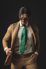 fashion elegant man with sunglasses looking down and pulling suit blazer