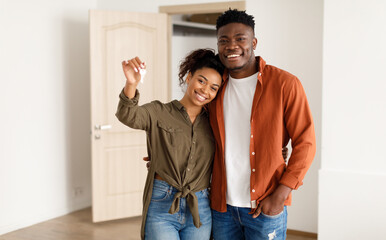 Real Estate. Cheerful African American Spouses Showing New House Key Smiling To Camera, Embracing...