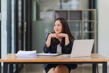 The Contemplative Executive: A young Asian businesswoman pauses for reflection amidst a bustling...