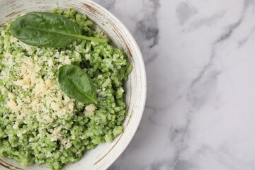 Tasty spinach risotto served on white marble table, top view. Space for text