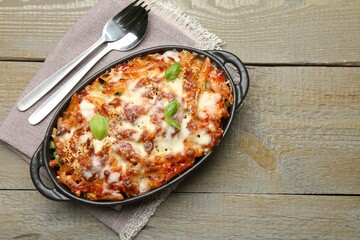 Delicious al forno pasta in baking dish on wooden table, top view. Space for text