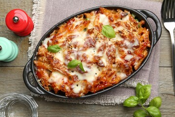 Delicious al forno pasta in baking dish on wooden table, flat lay