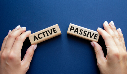 Active or Passive symbol. Concept word Active or Passive on wooden blocks. Businessman hand. Beautiful deep blue background. Business and Active or Passive concept. Copy space