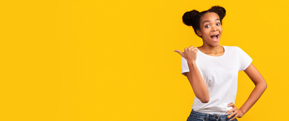 Special Offer. Enthusiastic black teen girl pointing to the side with thumb up. Panorama, free space