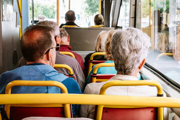 A group of elderly people sitting in the back seats of a bus, looking out the windows during a...