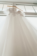 Elegant White Wedding Dress with Floral Embroidery Gracefully Displayed by a Window with a bottom-up angle