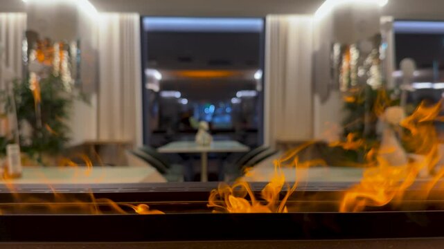 Close-up on bio fireplace burning inside restoran. Detail in interior, decorative fireplot at cozy modern hotel. Electric fireplace insert a stylish addition to any room. 