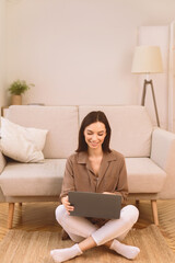 Surfing Internet. Happy smiling woman working on laptop computer, sitting on the floor with legs crossed, copyspace