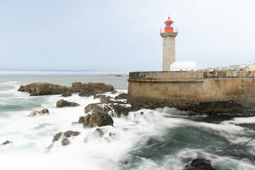 old lighthouse in the port of the city of porto with waves