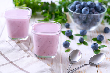 fresh natural homemade fruit yogurt in a glass jars with fresh blueberries on a light background, selective focus