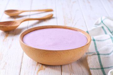 fruit yogurt in a wooden bowl with spoon on a light background, selective focus.
