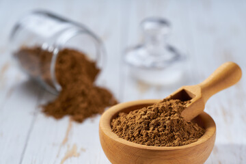 cinnamon powder in a wooden bowl  on a white wooden table, selective focus.
