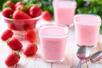 fresh natural homemade pink yogurt in a glass jars with fresh strawberry on a light background, selective focus.