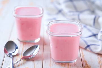 Homemade fruit pink smoothie in a glass jars with spoons on a rustic table, selective focus.