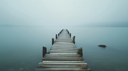 A wooden pier with a bridge leading to the water. The water is calm and the sky is overcast - Powered by Adobe