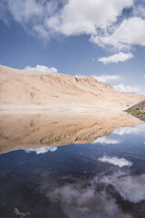 Lake Chukurkul with a mirror surface reflects rocky mountains and blue sky in the Tien Shan mountains in Pamir in Tajikistan, mirror landscape for the background