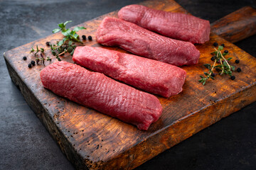 Raw lamb salmon fillet offered as close-up on a rustic wooden cutting board with dried cranberries and herbs with copy space © HLPhoto