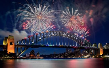 Obraz premium Fireworks explode over the Sydney Harbour Bridge and Opera House at night.