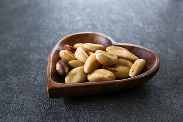 グレー背景の木製の皿にのせたブラジリアンナッツ