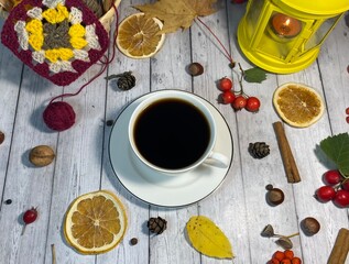 Cozy autumn photo with a cup of coffee, flashlight, crocheting, leaves and autumn decor