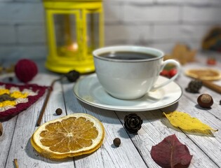 Cozy autumn photo with a cup of coffee, flashlight, crocheting, leaves and autumn decor
