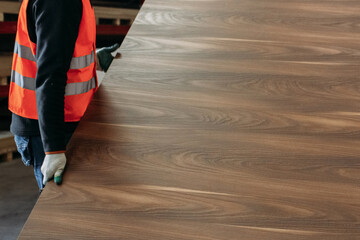 A Worker Carefully Handling a Large Piece of Wood in a Furniture Manufacturing Facility