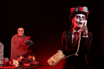 Lady talks on cord telephone at religious processions during Dia de los Muertos holiday. Woman uses...