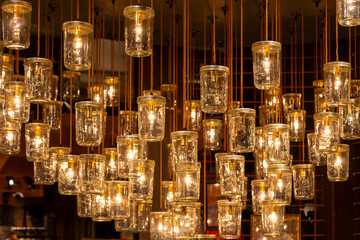cluster of mason jars hanging from the ceiling with lights inside
