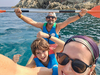 Family of three enjoying kayak activity at "la Fosca" Beach, one of the most amazing spots of "Costa Brava" Seaside in the Mediterranean sea, Catalonia, Spain.