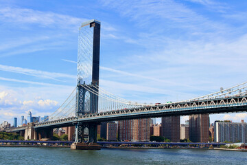 Main view of Manhattan bridge with iconic skyscrapers on background during a summer sunny day, NYC, USA.