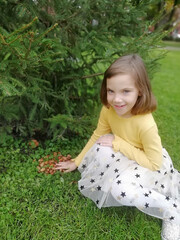 Little girl in the garden. Beautiful flowers roses. Cute lady watching thoughtfully. Child with big green eyes. Lovely flowers pink color. Green plant background. The charm of youth High quality photo