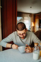 Young caucasian man eating corn flakes for breakfast at home
