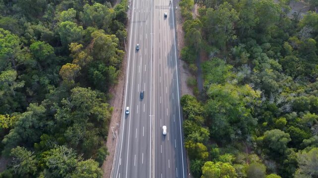 Autoestrada em Monsanto, Lisboa, ao p&ocirc;r do sol com tr&aacute;fego em movimento. O c&eacute;u alaranjado ilumina a estrada e os ve&iacute;culos, criando um contraste entre a natureza e a paisagem urbana.