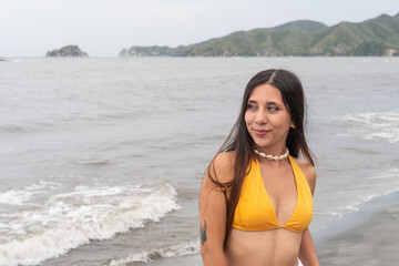 Young woman in yellow bikini enjoying a beach walk by the ocean