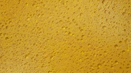 Close-up of water droplets on a smooth yellow surface creating an abstract texture and pattern