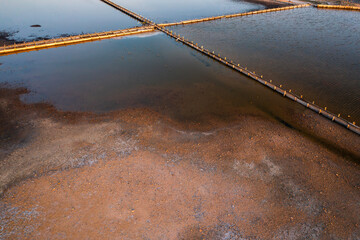Fototapeta premium Aerial view of salt pans at sunset showcasing water and land contrast