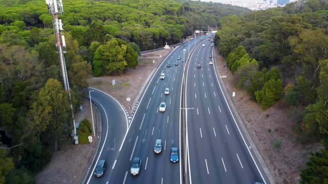 Autoestrada em Monsanto, Lisboa, ao p&ocirc;r do sol com tr&aacute;fego em movimento. O c&eacute;u alaranjado ilumina a estrada e os ve&iacute;culos, criando um contraste entre a natureza e a paisagem urbana.