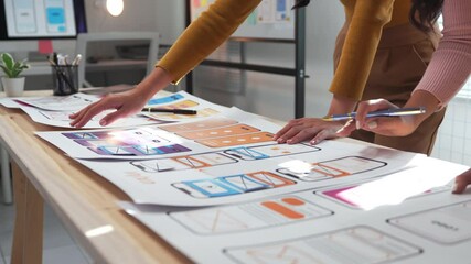 Two female ux designers collaborate on a mobile application prototype, discussing ideas and refining the wireframe at a table in a modern office environment